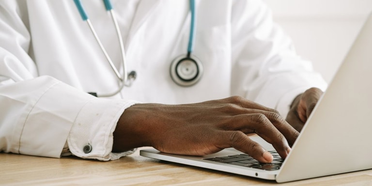 Medic lucrând pe laptop